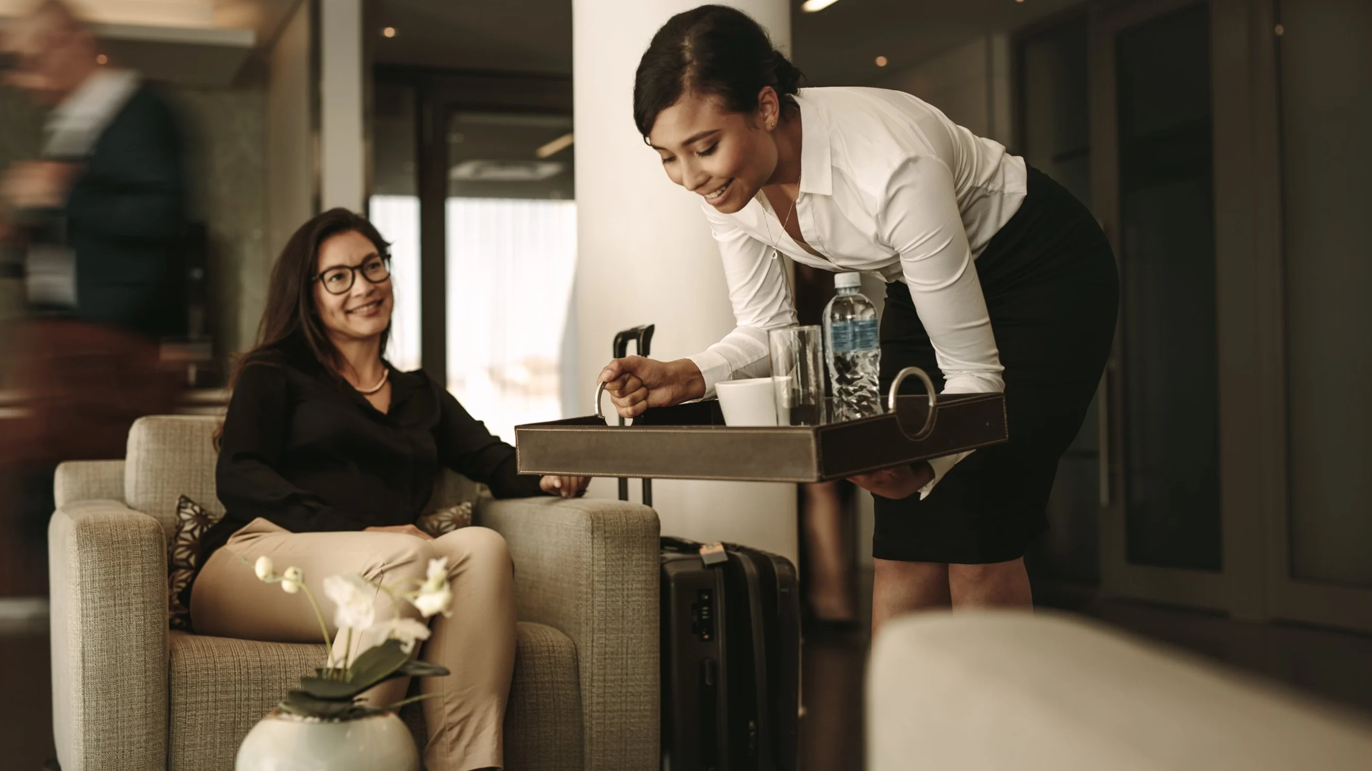 A traveller with luggage being met in an airport lounge